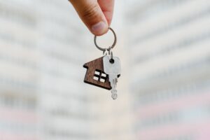 man holding key chain with a house and key, purchase of real estate